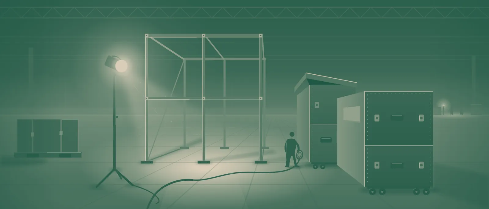 A booth stripped to its bare aluminum frame under a work light, packed road cases beside it — tear-down at dusk